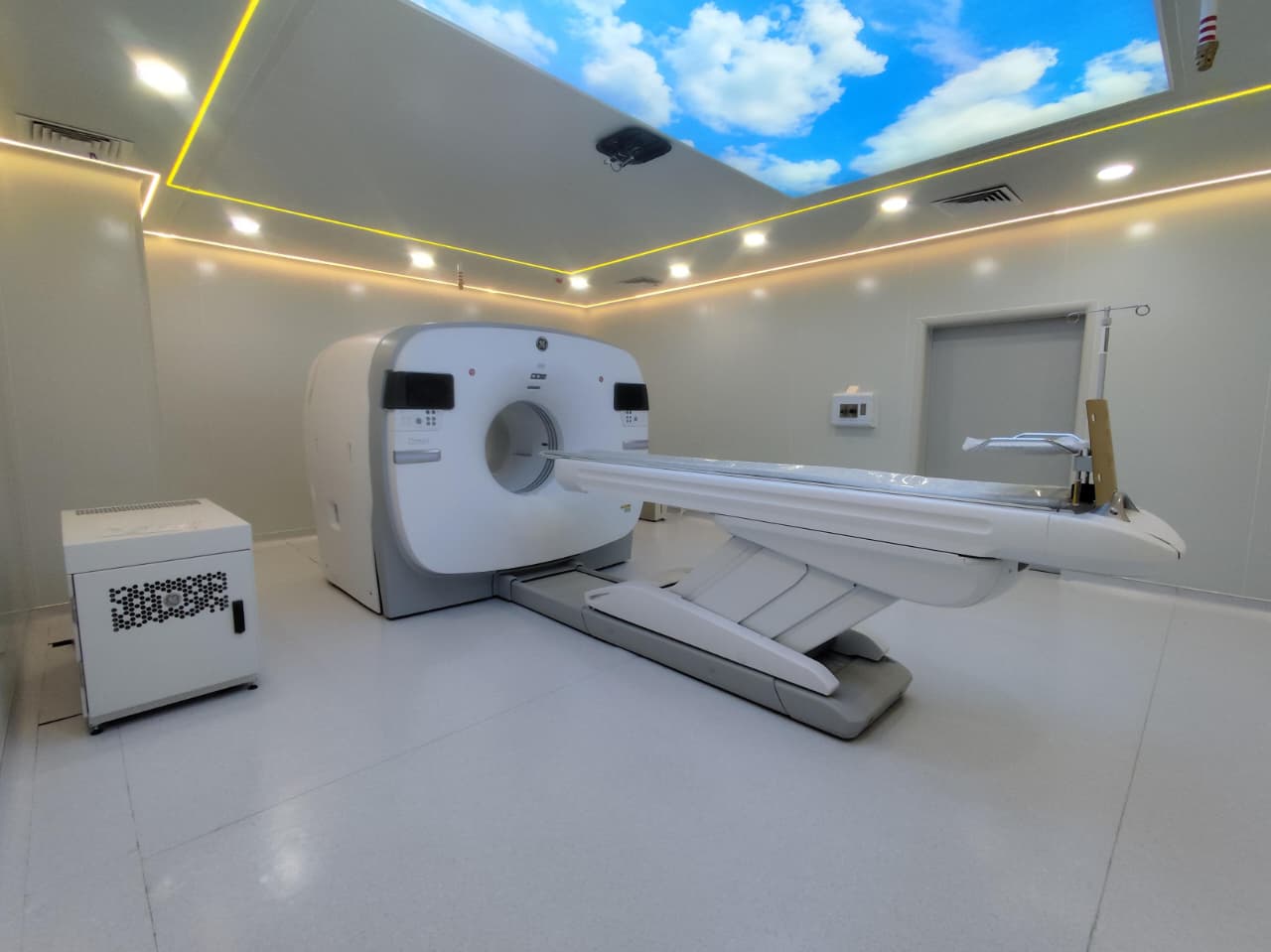 Completed PET-CT room lined with white sandwich panel walls and ceiling, with a backlit sky panel above the scanner